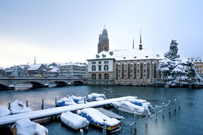 Bridge over river by buildings against sky