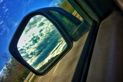 Reflection of clouds in side-view mirror