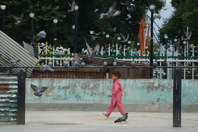 Side view of girl walking against trees