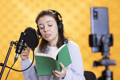 Portrait of young woman holding microphone while standing in gym