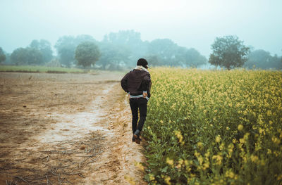 Rear view of woman walking on field