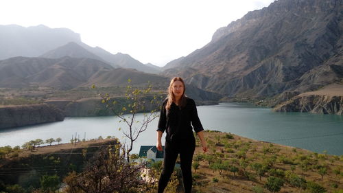 Woman standing on lake against mountains