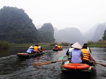 Rear view of people in boats on river