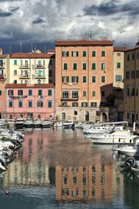 Sailboats moored on canal by buildings in city against sky