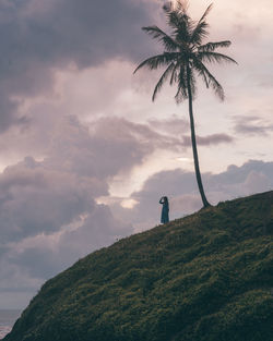 Low angle view of person standing on mountain against sky