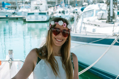 Portrait of smiling young woman wearing sunglasses at harbor
