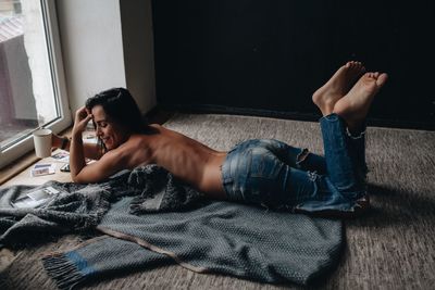 Shirtless woman lying on floor at home