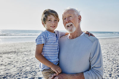 Grandfather carrying grandson on the beach