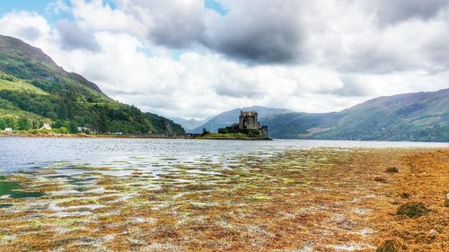 Scenic view of lake and mountains against cloudy sky