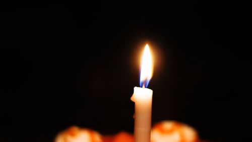 Close-up of illuminated candle in darkroom