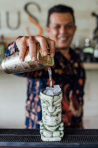 Bartender pour the drink to tiki glass