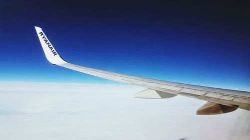 Cropped image of airplane flying against blue sky