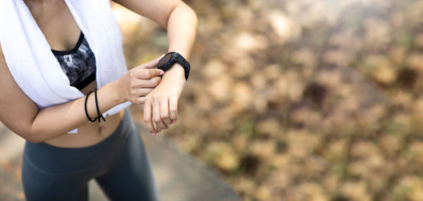 Midsection of woman holding camera while standing outdoors