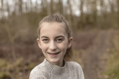 Close-up portrait of smiling teenage girl in forest