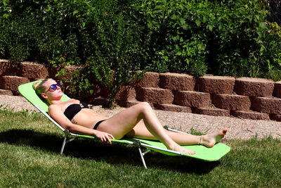 Woman in bikini lying on lounge chair