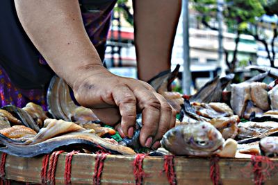 Midsection of woman arranging fish on market stall