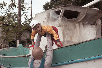 Rear view of man putting boy on boat