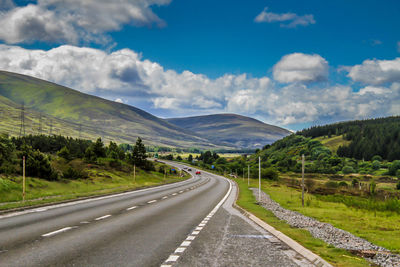 Road leading towards mountains against sky