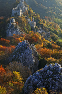 High angle view of trees and rocks during autumn, with a ruins of a fort on background