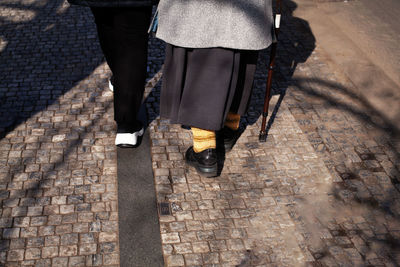 Elderly woman with a cane walking down the street, rearview. old couple holding hands together