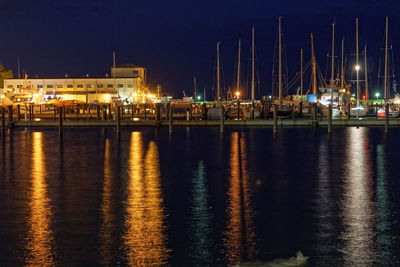 Sailboats moored in sea against sky at night