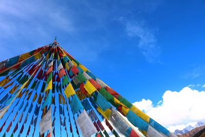 Low angle view of colorful prayer flags against blue sky