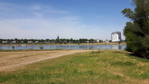 Scenic view of river by buildings against sky