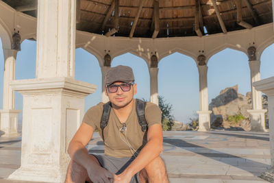 Portrait of man wearing sunglasses while siting in gazebo