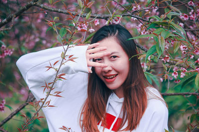 Portrait of smiling young woman with raised arm