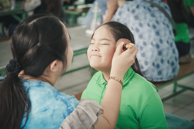 Mother applying make-up of daughter with brush