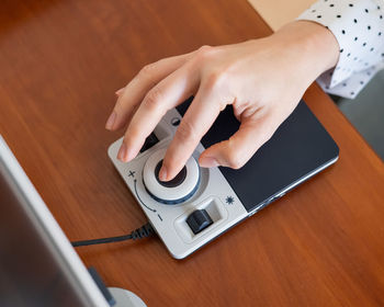 Cropped hands using magnifying device on table