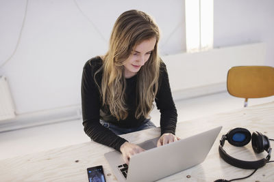 High angle view of female blogger using laptop at desk in office