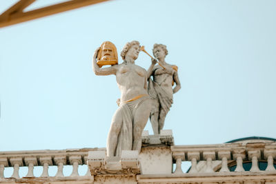 Low angle view of statues against building against clear sky