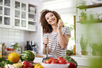 Smiling young woman eating food at home