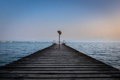 Pier over sea against sky during sunset