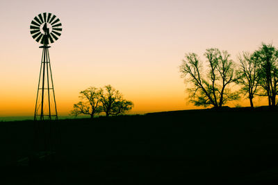 Silhouette windmill on field against sky during sunset