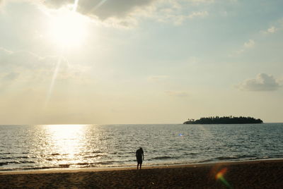 Silhouette person on beach against sky during sunset