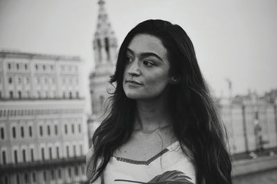 Portrait of young woman standing against city in background