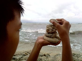 Midsection of man holding sea against sky