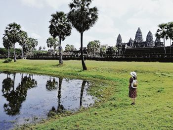 Man on field by lake against sky