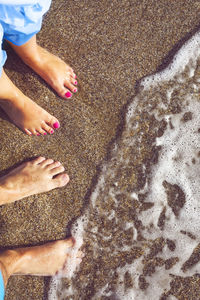 Low section of man and woman standing on beach