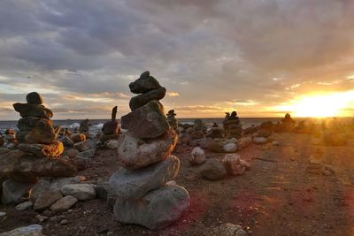 Stack of rocks on land against sky during sunset