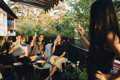Friends raising toast while enjoying drinks in party at back yard