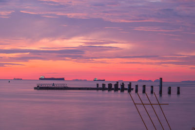 Pier on sea against sky during sunset