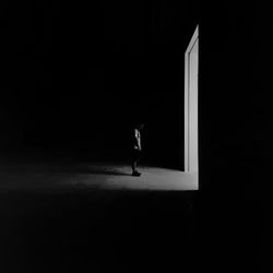 Side view of man standing by doorway in darkroom at night