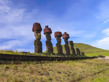 Statues on field against sky