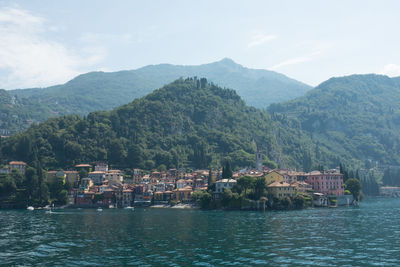 Houses by river and mountains against sky