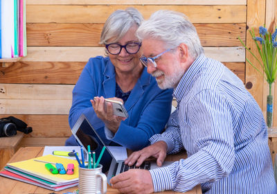 Senior couple using laptop and digital tablet while sitting on table