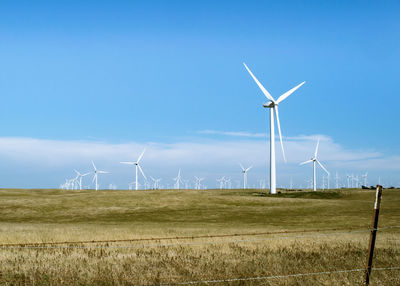 Windmills on field against sky