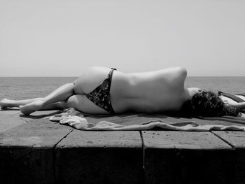 Rear view of sensuous topless woman relaxing by sea